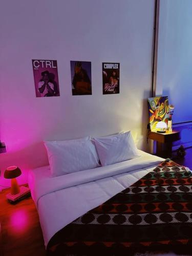 a bedroom with a bed with pink lighting and posters on the wall at Janatyy Guest House Suratthani in Suratthani