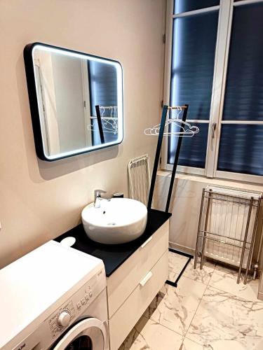 une salle de bain avec un lavabo et un miroir et une machine à laver dans l'établissement le bardo, à Aix-les-Bains