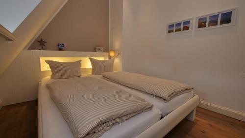 ein Bett mit zwei Kissen darauf in einem Zimmer in der Unterkunft Landhaus Strandhafer HT 1 in Wenningstedt-Braderup