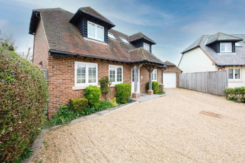 a brick house with a driveway in front of it at Modern & stylish seaside family home in Chichester
