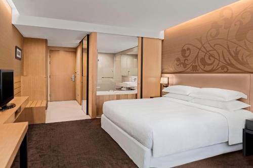 a bedroom with a large white bed and a bathroom at Four Points by Sheraton Bangkok, Sukhumvit 15 in Bangkok