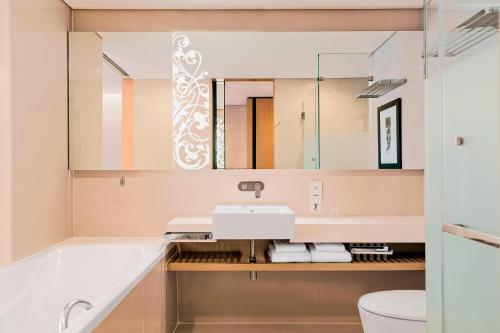 a bathroom with a sink and a tub and a mirror at Four Points by Sheraton Bangkok, Sukhumvit 15 in Bangkok