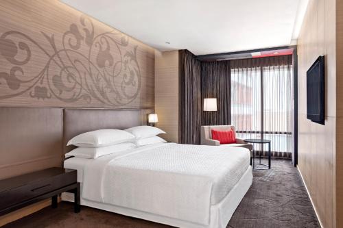 a bedroom with a large white bed and a chair at Four Points by Sheraton Bangkok, Sukhumvit 15 in Bangkok