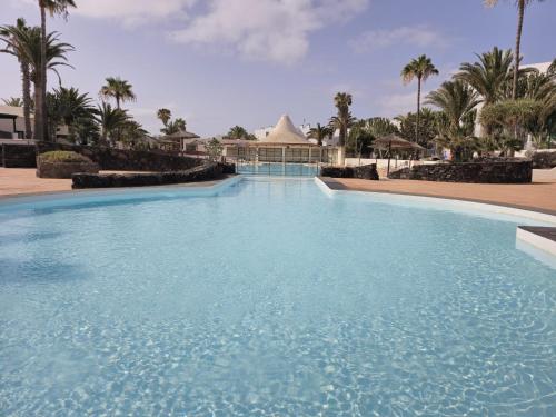 a large swimming pool with a building in the background at Bungalow Aqua Sol - Playa Roca residence - Sea front access - Free AC - WiFi in Costa Teguise