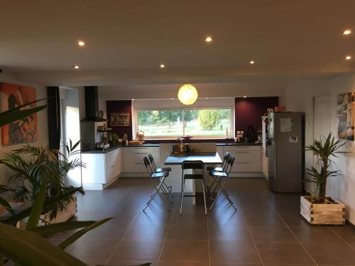 une cuisine avec une table et un réfrigérateur dans l'établissement La Maison de Benjamin, à La Chapelle-Saint-Aubert
