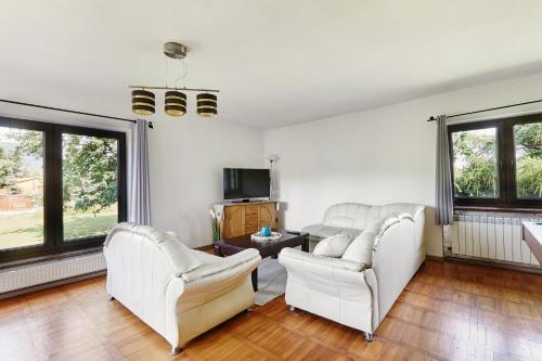 a living room with white furniture and large windows at Dom Kubicowka in Rybarzowice