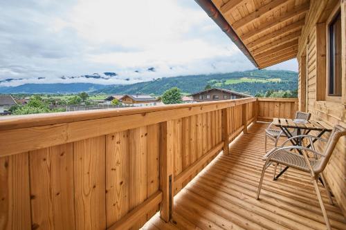 a wooden deck with chairs and a table on it at Platzhirsch Rooms - B&B - SELF CHECK-IN in Piesendorf