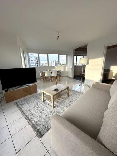 ein Wohnzimmer mit Sofa und Tisch in der Unterkunft Superbe T4 Vue, Métro Commerces in Créteil