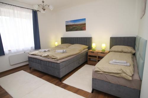 two beds in a bedroom with two lamps and a window at Tulipán Vendégház in Polány