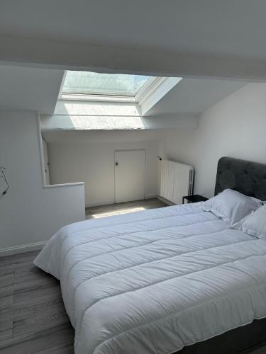 - une chambre avec un grand lit blanc et une lucarne dans l'établissement Duplex cosi, à Pierrefitte-sur-Seine