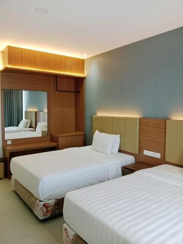 a hotel room with two beds and a mirror at Grand Cahaya Hotel Pangandaran in Pangandaran