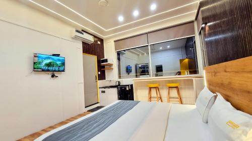 a bedroom with a bed and a kitchen with stools at Stayinn Nest in Bhopal