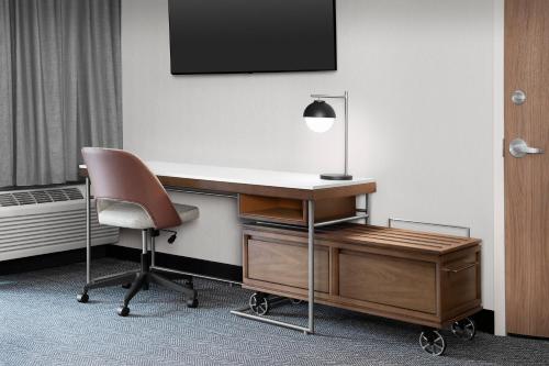 a desk with a chair and a tv on a wall at Courtyard by Marriott Portland Tigard in Tigard
