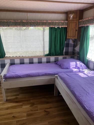 a bedroom with two beds with purple sheets and a window at 4U Pokój w domku holenderskim Rooms in Tinyhouse in Zgorzelec