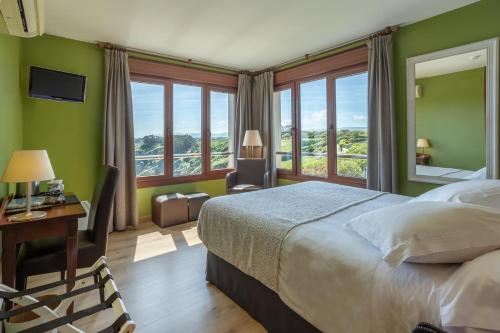 a bedroom with a bed and a desk and windows at La Colina in Gijón