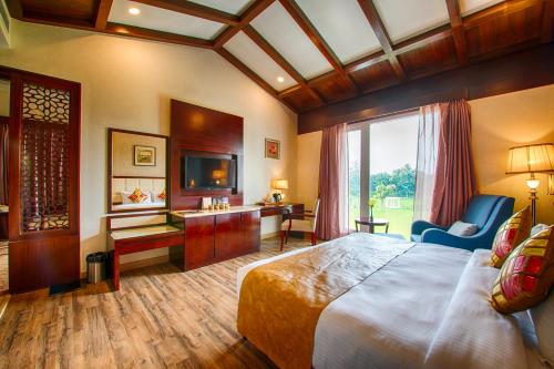 a hotel room with a large bed and a television at Tiaraa Hotels & Resorts in Rāmnagar