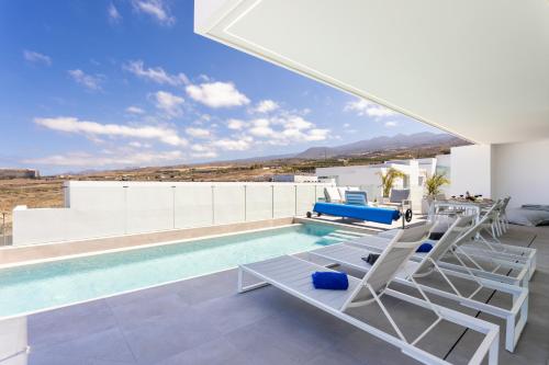una casa con piscina con sedie e un parasole per piscina di Sybaris Villa 09 by Smart Holiday ad Adeje