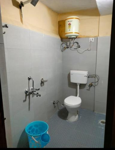 a bathroom with a toilet with a bucket on the wall at Gate valley home stay in Dalhousie