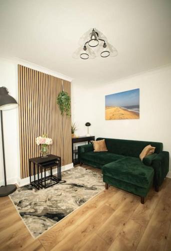 a living room with a green couch and a table at Spacious - Sleeps 5 - Garden - Close To Sea in Gorleston-on-Sea