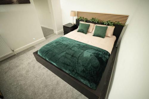 a bedroom with a large bed with a green blanket at Spacious - Sleeps 5 - Garden - Close To Sea in Gorleston-on-Sea