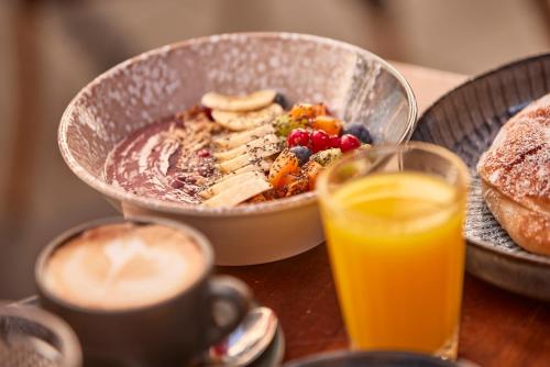 Una mesa con un tazón de comida para desayunar y un vaso de jugo de naranja. en Hotel Cort, en Palma de Mallorca