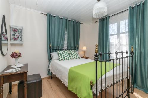 a bedroom with a bed with green curtains and a window at Butterfly House by "elite" in Pigadhákia