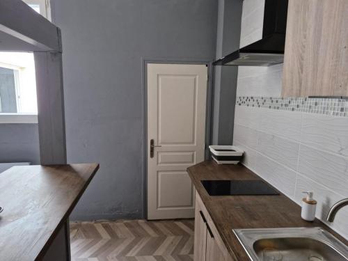 une petite cuisine avec un évier et une porte. dans l'établissement Grand Studio Centre de Cambrai, à Cambrai