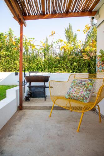 a yellow bench sitting on a patio with a grill at Rus In De Rust in De Rust