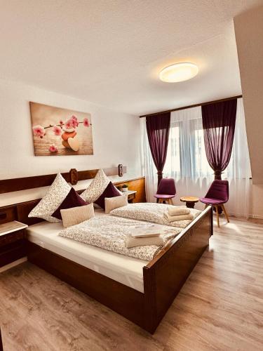 a bedroom with a large bed and purple chairs at HAUS BENICO -Pension- in Ernst