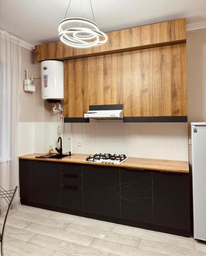 a kitchen with black cabinets and a white refrigerator at Apart Hotel in Shymkent