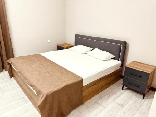 a bedroom with a large bed with a nightstand and a bed sidx sidx sidx at Apart Hotel in Shymkent