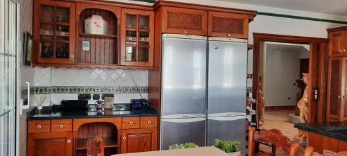 una cucina con mobili in legno e frigoriferi in acciaio inossidabile di Luxury Tropical Villa in Grao Benicassim a Grao de Castellón