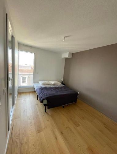 une chambre avec un lit et une grande fenêtre dans l'établissement Bel appart' de 47m2 au coeur de Bordeaux, à Bordeaux