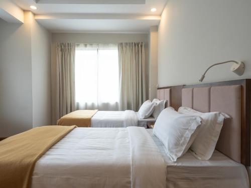 a hotel room with two beds and a window at Hotel Samye - Best Hotel In Thimphu in Thimphu