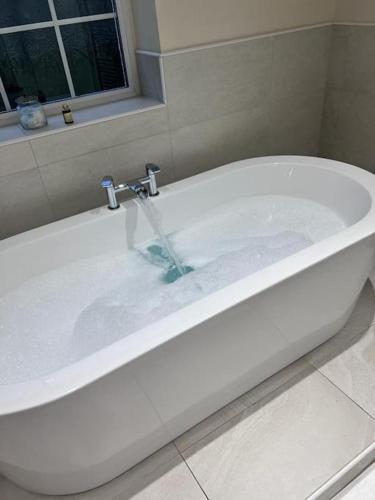 a bath tub filled with water in a bathroom at Orme Villa, Hot Tub, Llandudno, Stunning Views , sleeps 12 in Llandudno
