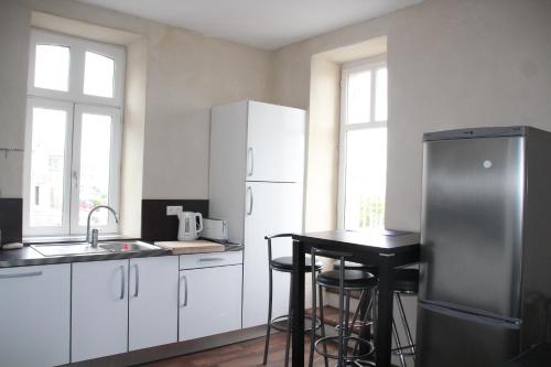 a kitchen with white cabinets and a refrigerator and a table at La Maison du Port, vue mer, jardin et parking in Roscoff