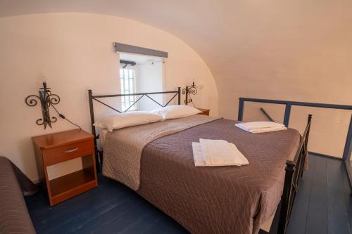 a bedroom with a bed and a night stand with towels on it at Vesuvio Inn Guest House e Wine Experience in Boscotrecase