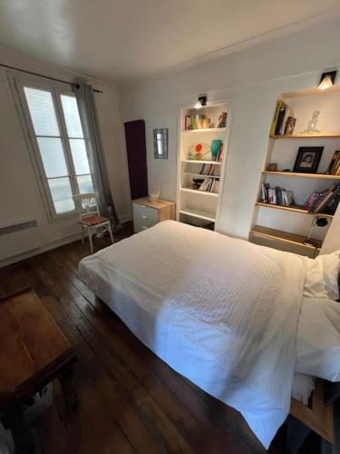 une chambre avec un lit blanc et un parquet dans l'établissement Appartement central Paris, à Paris
