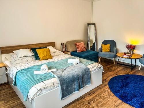 a bedroom with a bed and two chairs at Villa Blue City Apartman in Szekszárd