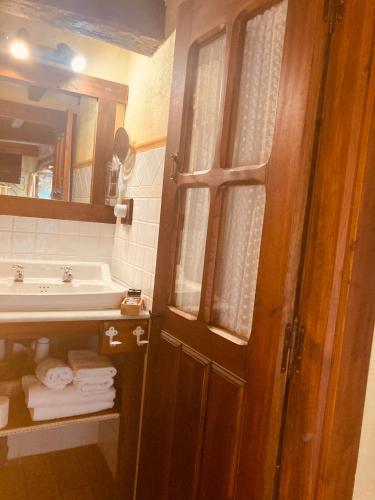 a bathroom with a sink and a door with towels at Posada la Trebede in Perrozo