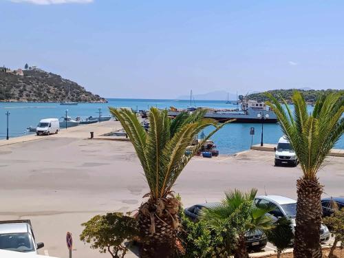 two palm trees in a parking lot next to the water at Hermione Horizon in Ermioni