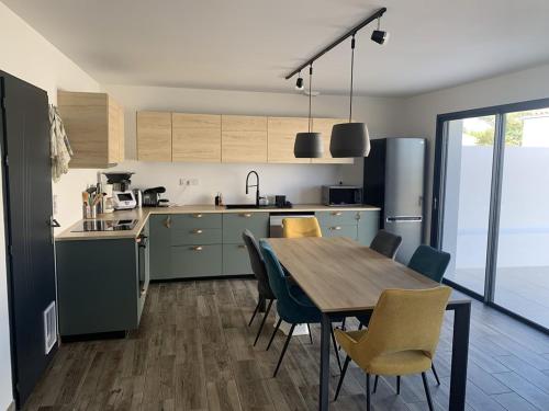 une cuisine avec une table et des chaises en bois ainsi qu'une table et une salle à manger dans l'établissement La Villa Océane de la Sauzaie, à Bretignolles-sur-Mer