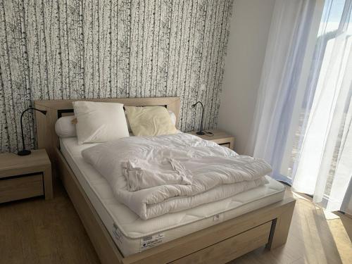 un lit avec des draps blancs et des oreillers dans une chambre dans l'établissement La Villa Océane de la Sauzaie, à Bretignolles-sur-Mer