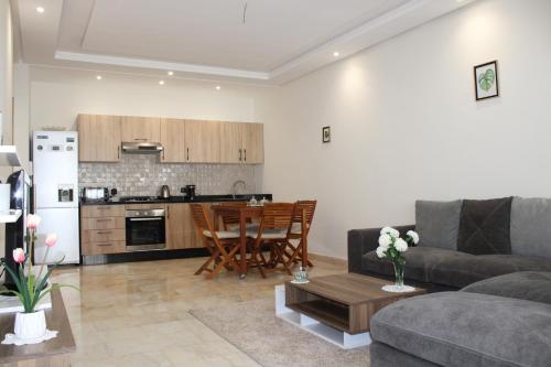 a living room with a couch and a table and a kitchen at Très Joli rez-de-jardin à 2 min de la plage Les Sablettes in Mohammedia