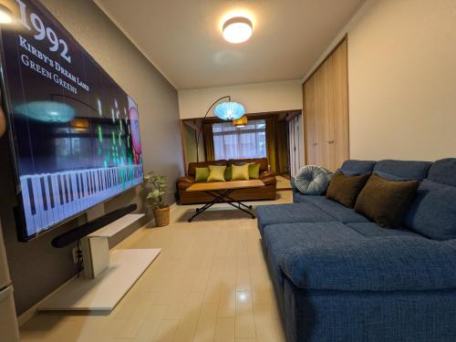 a living room with a blue couch and a flat screen tv at Villa Castle Ginza ヴィラ キャッスル 銀座 in Hikone