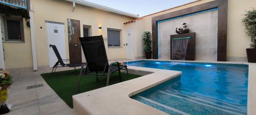 a swimming pool with two chairs and a table next to it at AniCa II, el lugar de la Mancha in Argamasilla de Alba