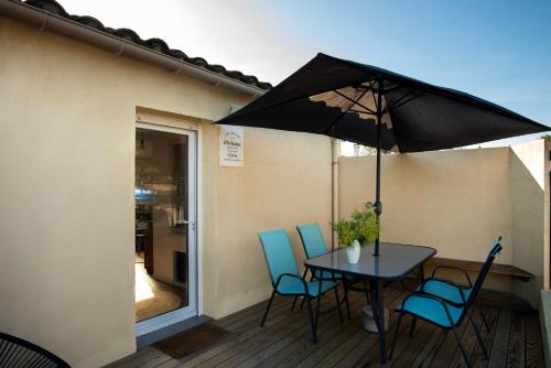 une table et des chaises avec un parasol sur une terrasse dans l'établissement Charmant havre de paix à 10 mn de Carcassonne, mer, montagne et trésors de l'unesco à portée de main, à Villemoustaussou
