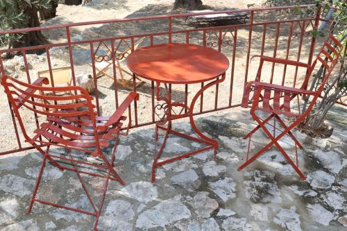 two chairs and a table next to a fence at Δωμάτια Κόκκινος Πύργος in Plomarion