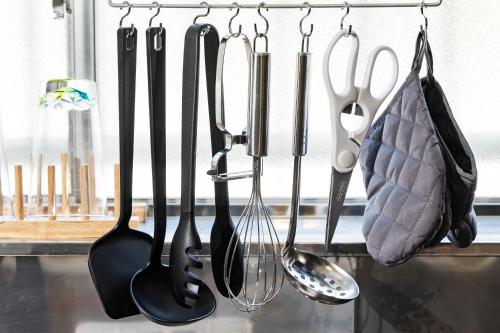 a bunch of kitchen utensils hanging on a wall at Holiday cottage BEPPU ICHIYA in Beppu