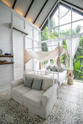 a living room with a couch and a large window at Proud Phu Fah Maerim Resort in Mae Rim